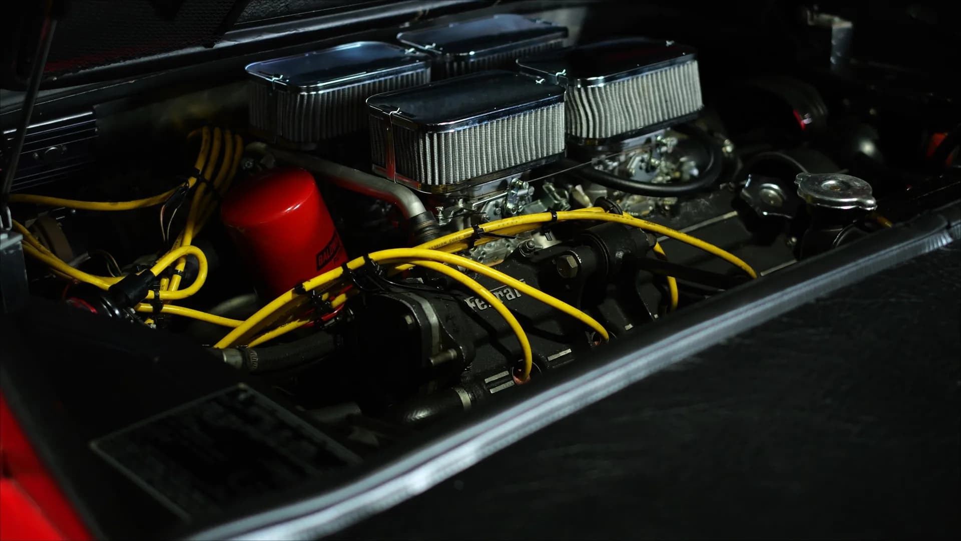 Engine bay of a 1978 Ferrari 308 GTS showing four Weber carburetors with individual air filters and yellow ignition leads