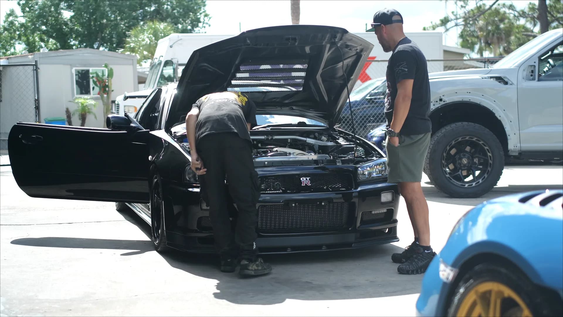 Black 1999 R34 Nissan Skyline GT-R with the hood raised during turbocharger work at Corsa Automotive